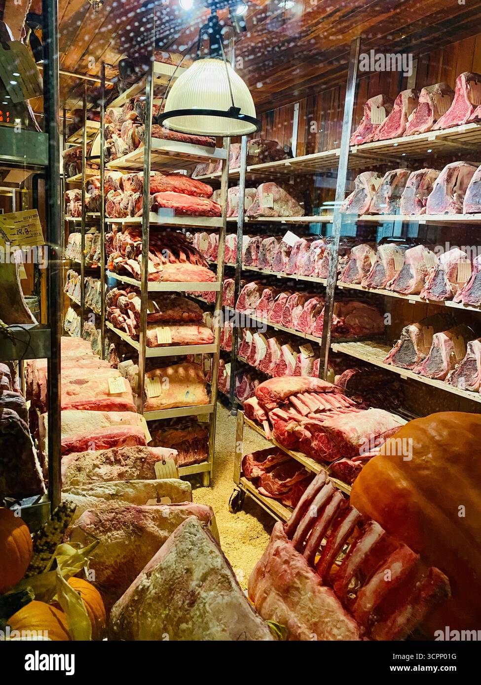 Dry Aging Room mit Ribeye- und Tomahawk-Steaks auf Metallregalen - Smartphone-aufgenommenes Stockfoto