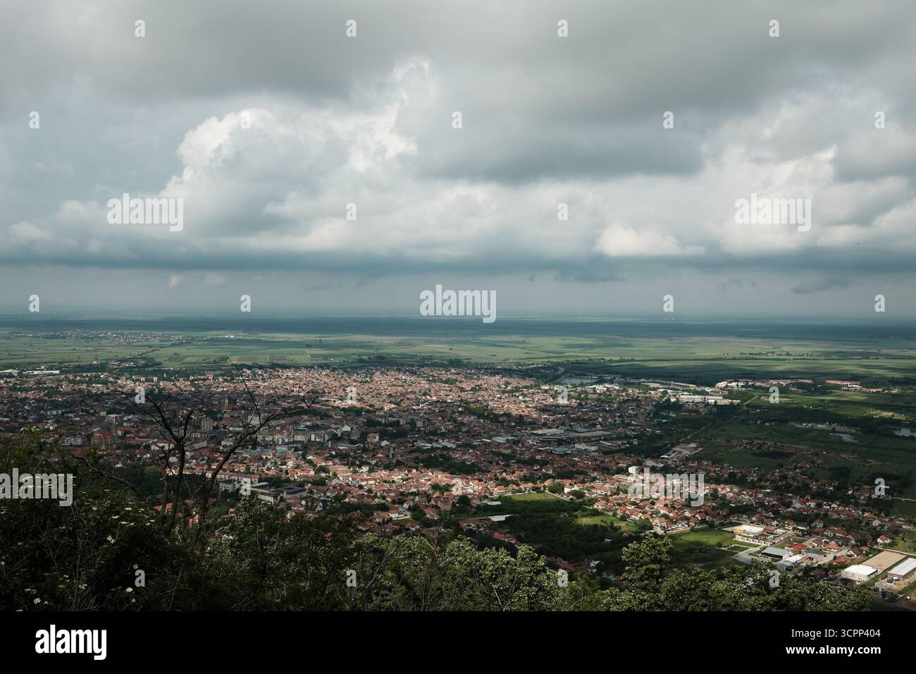 Großer Panoramablick auf Vrsac und die umliegende serbische Landschaft unter einem dramatischen bewölkten Himmel im Frühling. Stockfoto