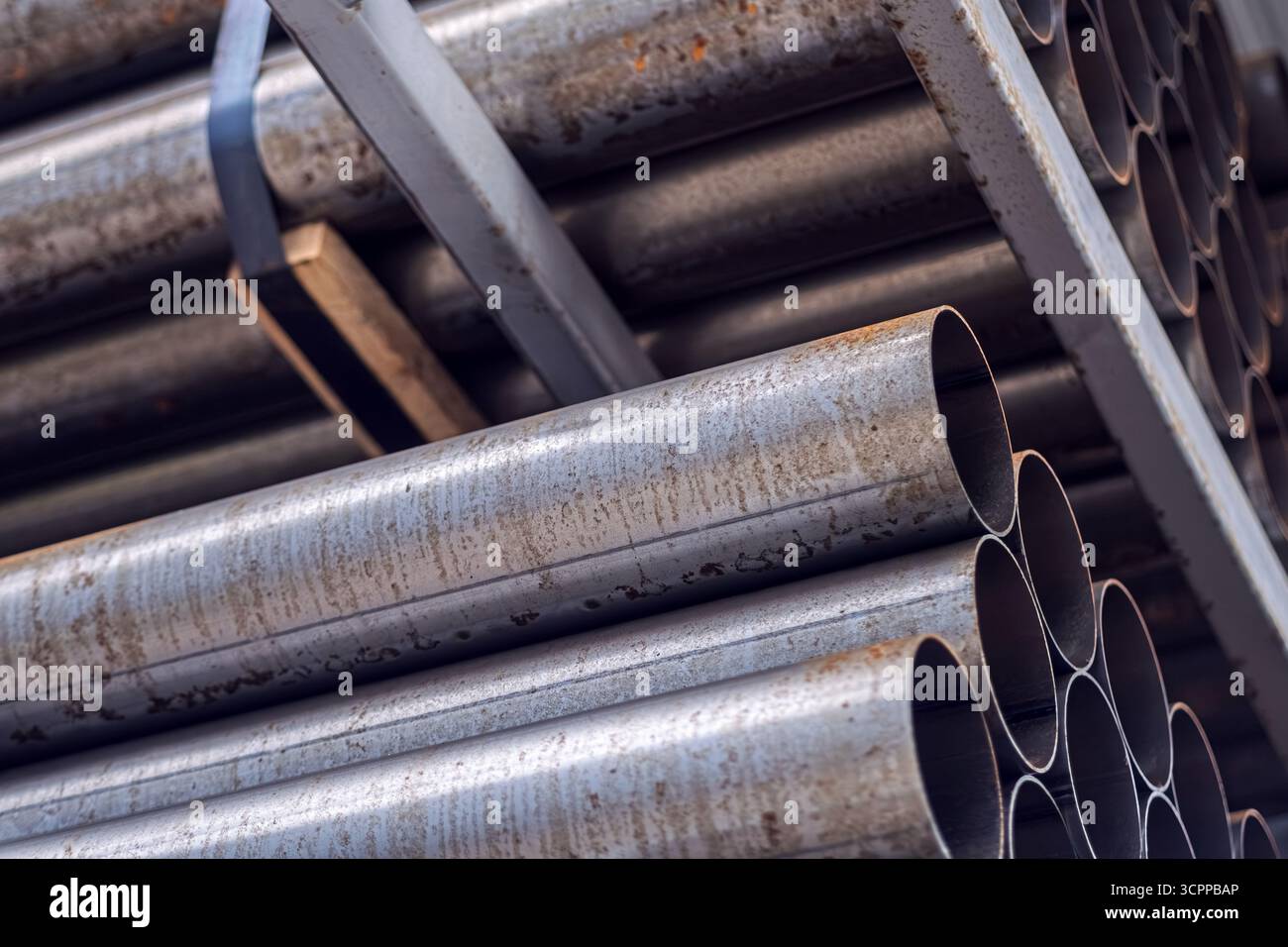 Nahaufnahme von gestapelten Metallrohren in einem Lagergebäude. Dieses Bild der Industrie hebt die Strukturen und Details von Stahlrohren hervor. Stockfoto