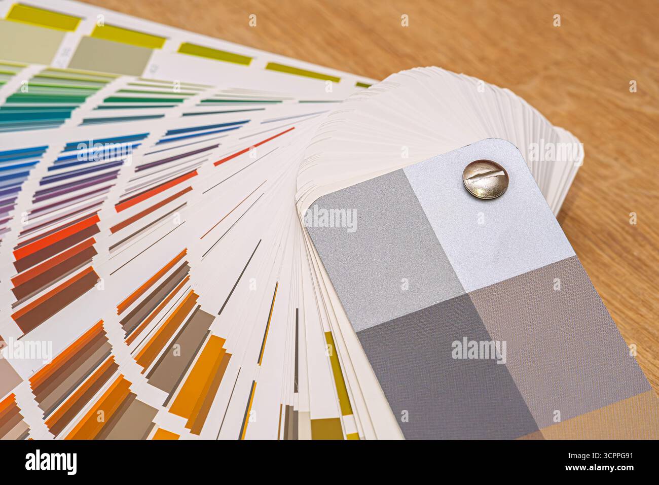 Fächerdeck mit Farbmuster für Design und Druck. Eine detaillierte Nahaufnahme eines Fächerdecks mit Farbmuster, verteilt auf einer Holzoberfläche. Stockfoto