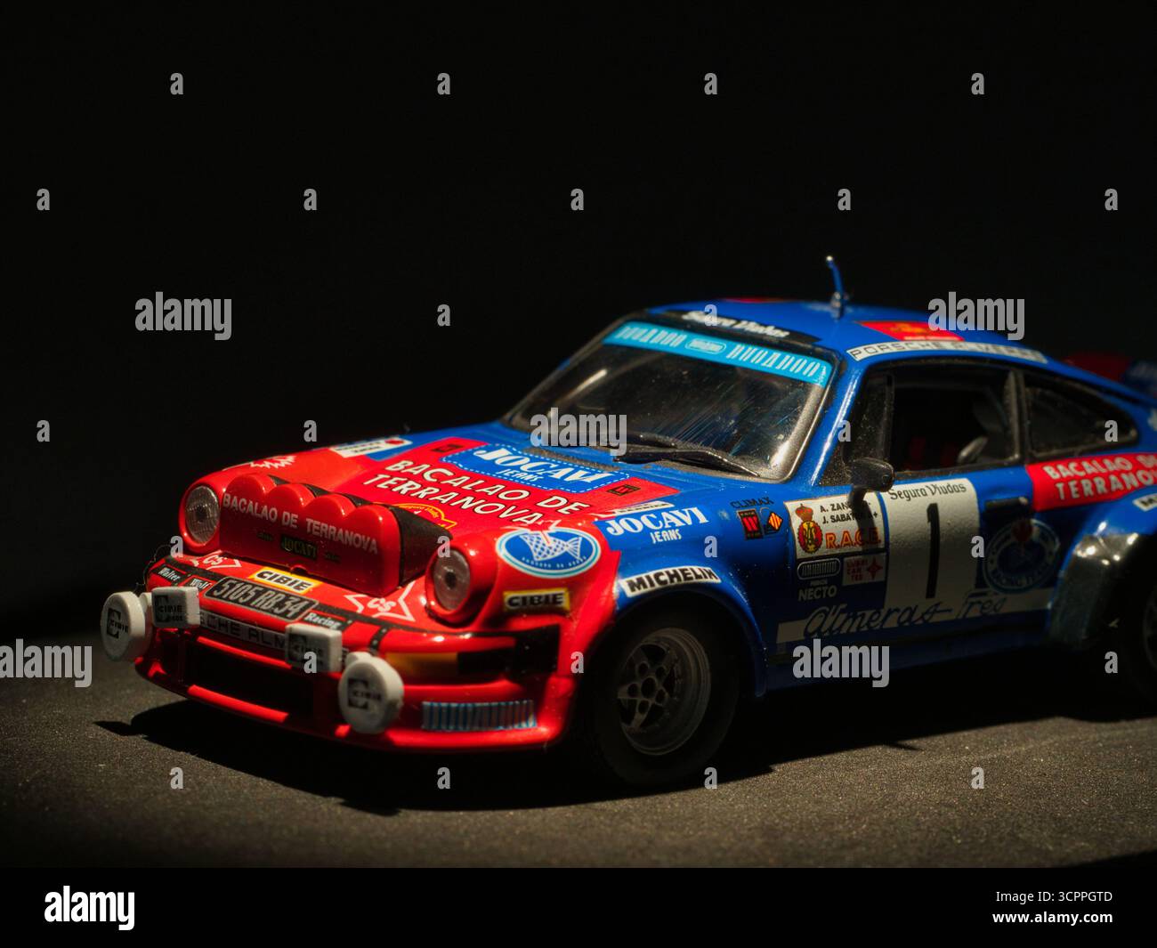 Oldtimer-Rallye-Modell dunkler Hintergrund - Nahaufnahme einer detaillierten, bunten Miniatur-Nachbildung eines klassischen Porsche-Rallye-Autos mit Sponsoring-Abziehbildern, d Stockfoto