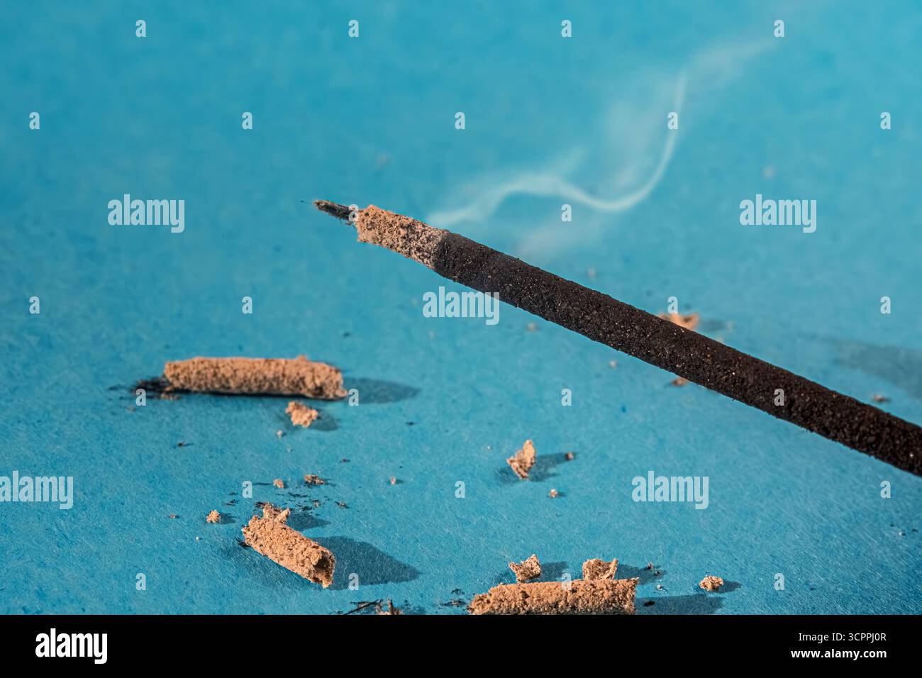 Räucherstäbchen mit aufsteigendem Rauch. Der leuchtend blaue Hintergrund verbessert die Szene. Ein Gefühl der Ruhe und Entspannung des Räucherstäbchens. Stockfoto