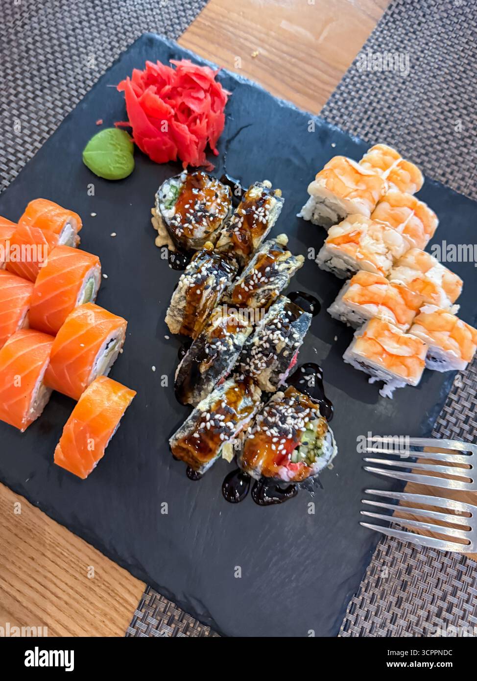 Verschiedene Sushi-Brötchen auf einem Steingericht mit frischem Wasabi und eingelegtem Ingwer, japanische Küche und Gourmet-Speisen - Smartphone-aufgenommenes Stockfoto