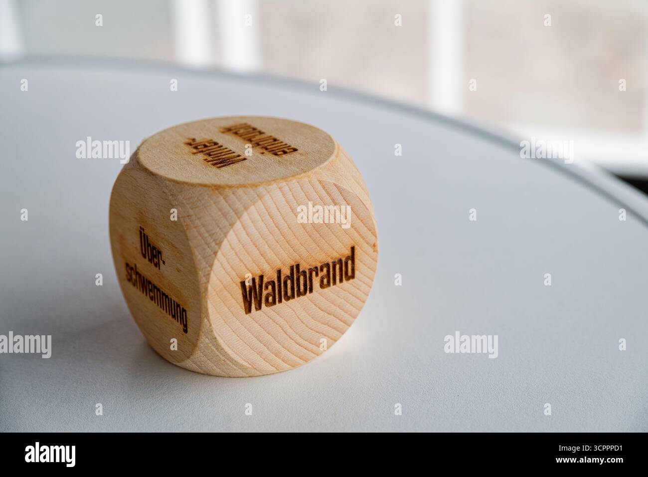 Kleiner geschnitzter Holzwürfel liegt auf einer glatten Oberfläche mit glatten Ecken und einer verbrannten Inschrift mit Lauffeuer in deutscher Sprache Waldbrand auf der fr Stockfoto