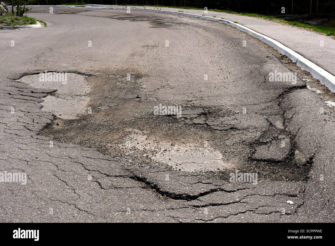 Gebrochene Asphaltplatte und Schlaglöcher auf der beschädigten Straßenoberfläche. Keine Personen. Stockfoto