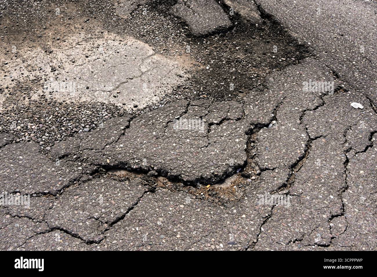 Gebrochene Asphaltplatte und Schlaglöcher auf der beschädigten Straßenoberfläche. Keine Personen. Stockfoto