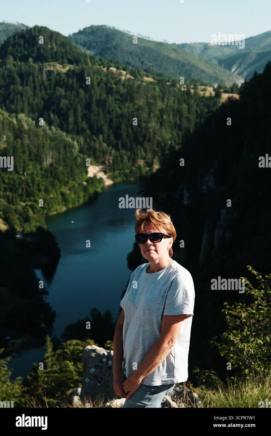Porträt einer Frau in lässigem Outfit und Sonnenbrille vor dem Spajici-See im Tara-Nationalpark, Serbien. Stockfoto