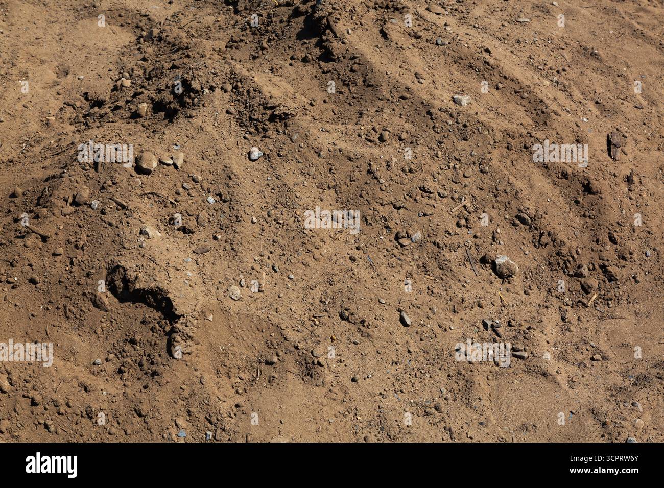 Blick von oben auf einen Hügel aus braunem Boden mit verstreuten kleinen Bruchstücken auf der Baustelle. Stockfoto
