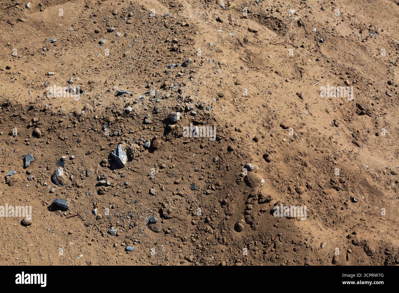 Blick von oben auf einen Hügel aus braunem Boden mit verstreuten kleinen Bruchstücken auf der Baustelle. Stockfoto
