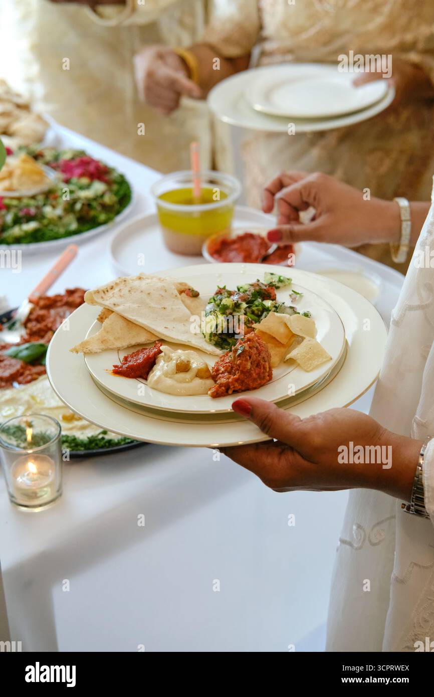 Eine Frau serviert auf einer intimen indianischen Hochzeit ein Tafelgericht, bei dem traditionelle indische Aromen mit moderner Präsentation kombiniert werden Stockfoto