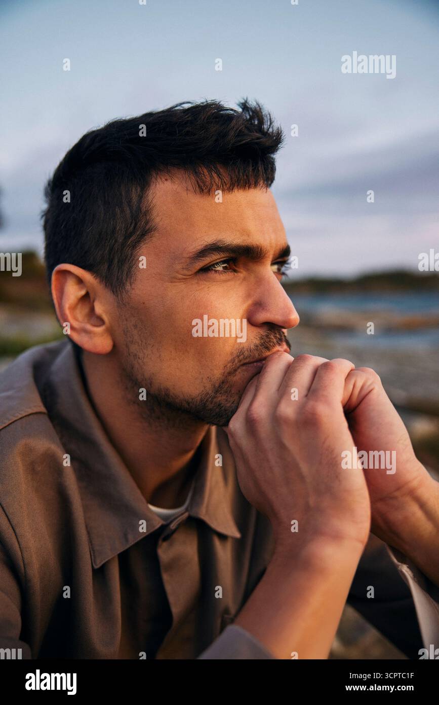 Nachdenklicher Mann mit Hand am Kinn wegschauen Stockfoto