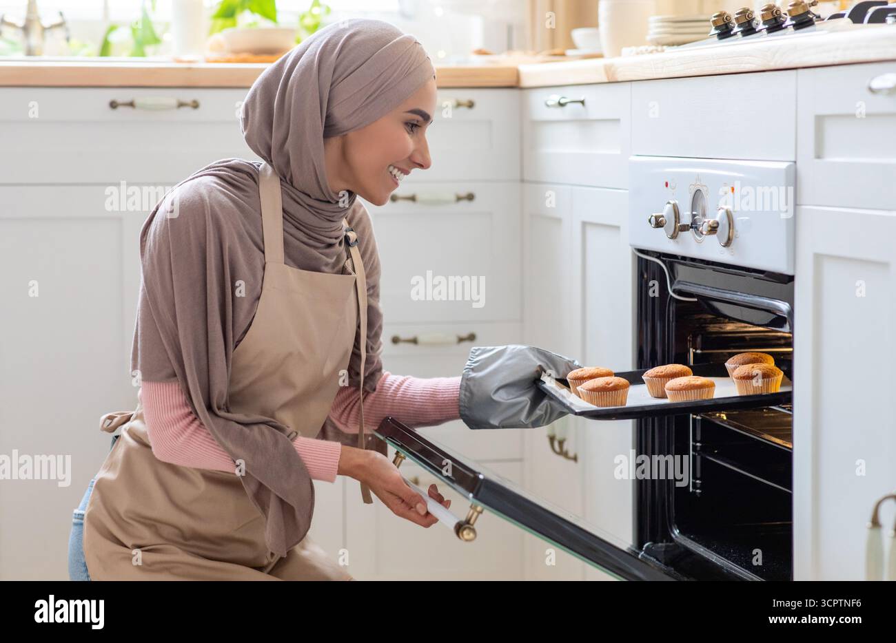 Junge Islamische Hausfrau In Hijab Und Schürze Backen Muffins In Küche Stockfoto