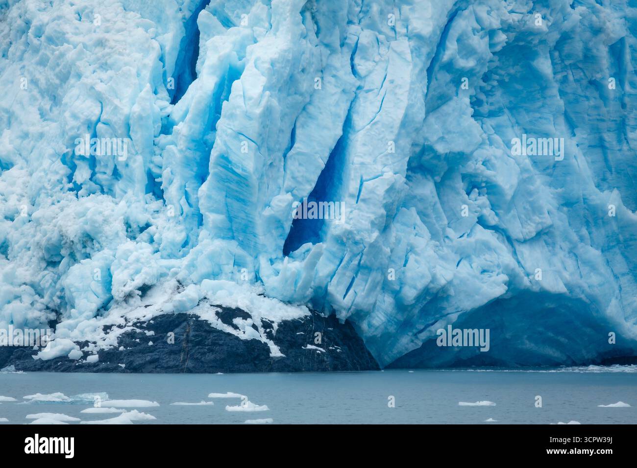 Ein Gletscher trifft auf den Ozean, mit Eisbrocken im Wasser, die die natürliche Schönheit und die Auswirkungen des Klimawandels demonstrieren. Stockfoto