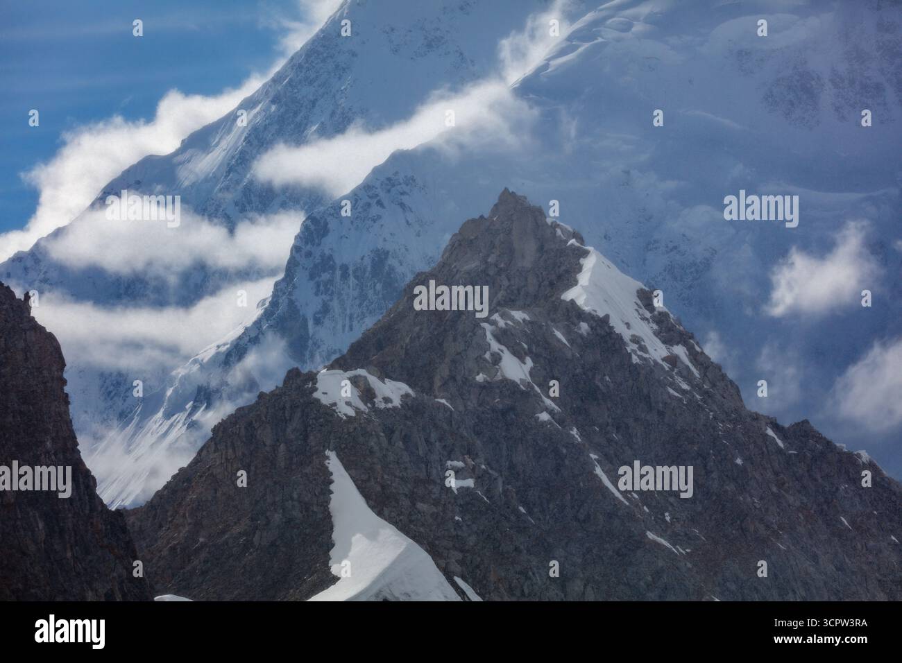 Eine majestätische Bergkette, die teilweise von Wolken bedeckt ist, zeigt die raue Schönheit und die gewaltige Herausforderung der majestätischen Gipfel der Natur. Stockfoto