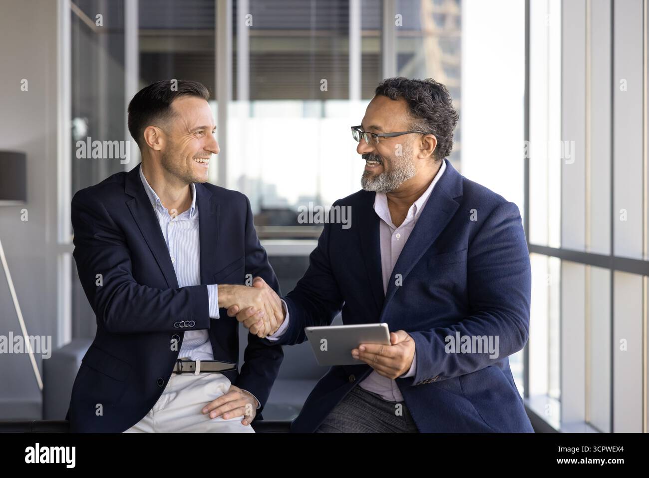In der modernen Bürolounge tauschen sich zwei selbstbewusste Profis aus Stockfoto