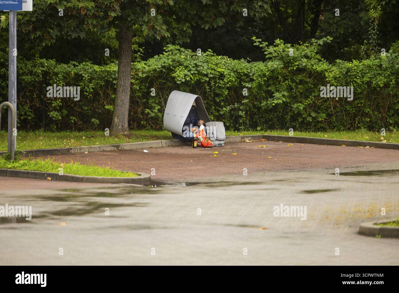 Ein Obdachloser sucht Schutz vor Regen in einem Supermarkt-Parkplatz in Dresden, Sachsen, Deutschland Stockfoto