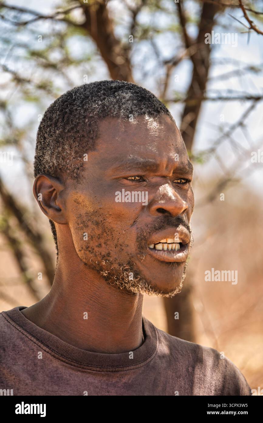 Einzelner afrikanischer Mann, Dorf, draußen in der Wildnis, blauem Himmel und Akazienbäumen Stockfoto