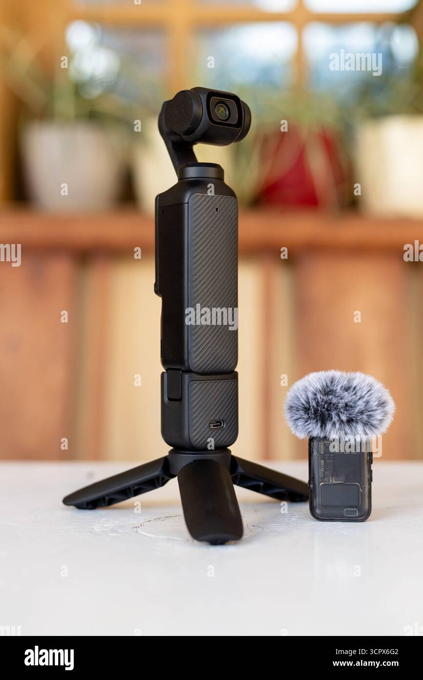 Tragbare Gimbal-Kamera mit Stativ und drahtlosem Mikrofon auf weißem Tisch mit unscharfem Hintergrund Stockfoto