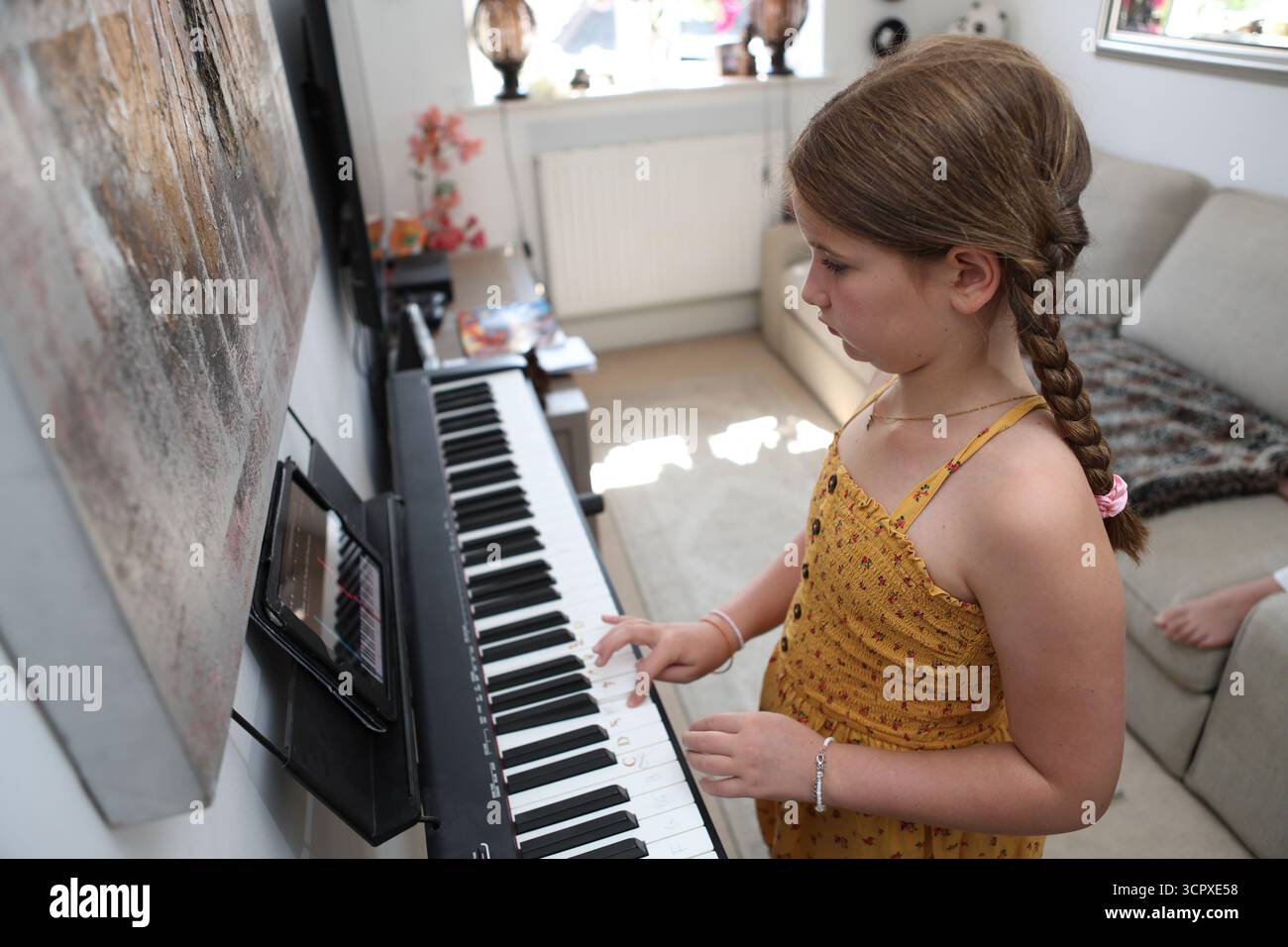 Mädchen spielt Musik-Tastatur mit Tablet ipad mit App, um die Sequenz der zu spielenden Tasten zu erlernen Stockfoto