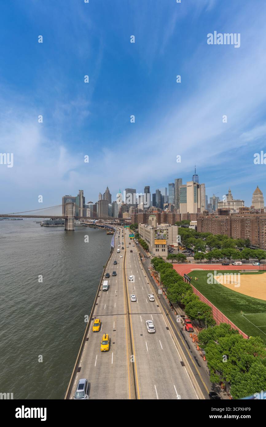 Weite Aussicht auf die Skyline von Manhattan mit Brooklyn Bridge und FDR Drive entlang des East River an einem sonnigen Tag in New York City. Juni 2025. Stockfoto