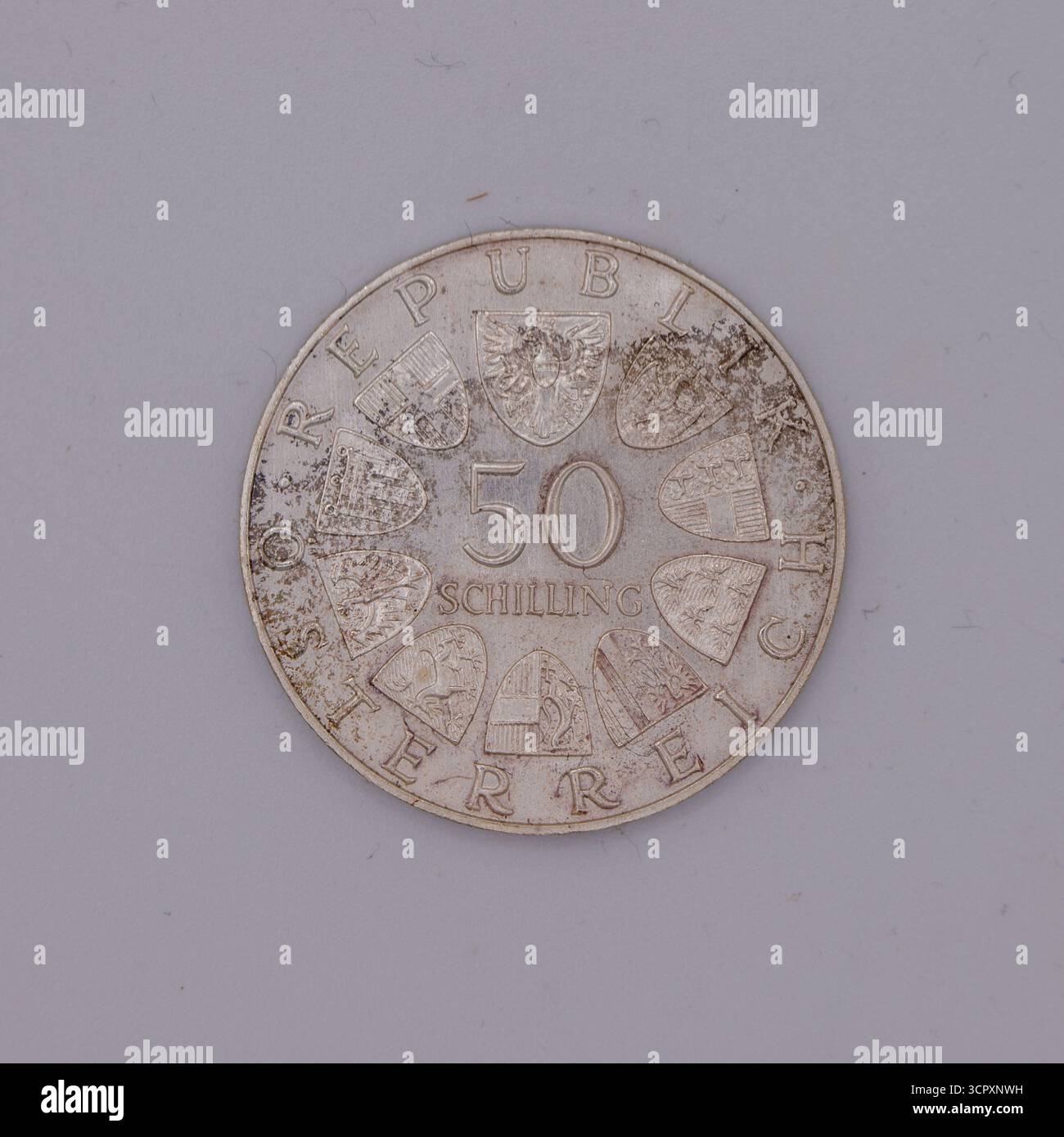 Nahaufnahme einer angetrübten Silbermünze mit dem österreichischen Wappen und Provinzschilden, Text „Republik Österreich“ und Wert „50 Schilling“. Stockfoto