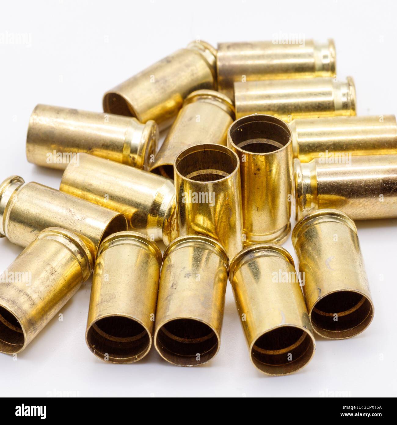 Ein Stapel gebrauchter Messingkugeln ist auf einer weißen Oberfläche verstreut und zeigt einen warmen, goldenen metallischen Glanz und etwas Schmutz. Stockfoto