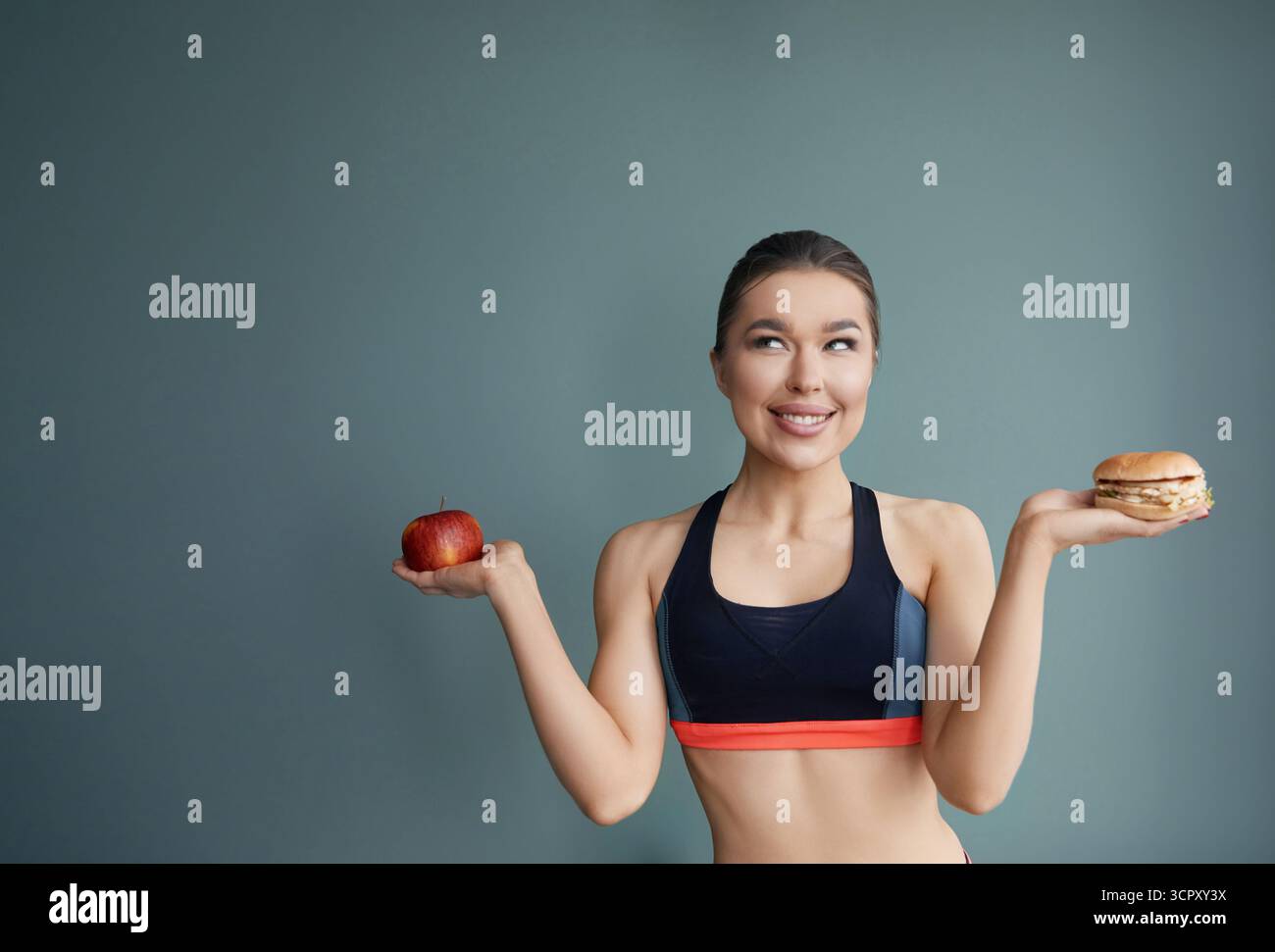 Diätkonzept. Gesunde Ernährung. Frau, die die Wahl zwischen Apfel und Hamburger trifft. Stockfoto