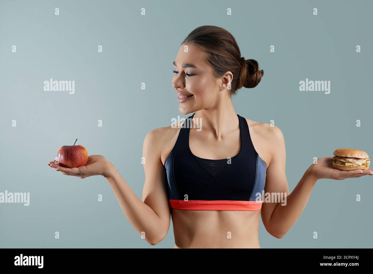 Frau, die zwischen Apfel und Hamburger wählen kann. Diät-Konzept. Gesunde Ernährung, Stockfoto