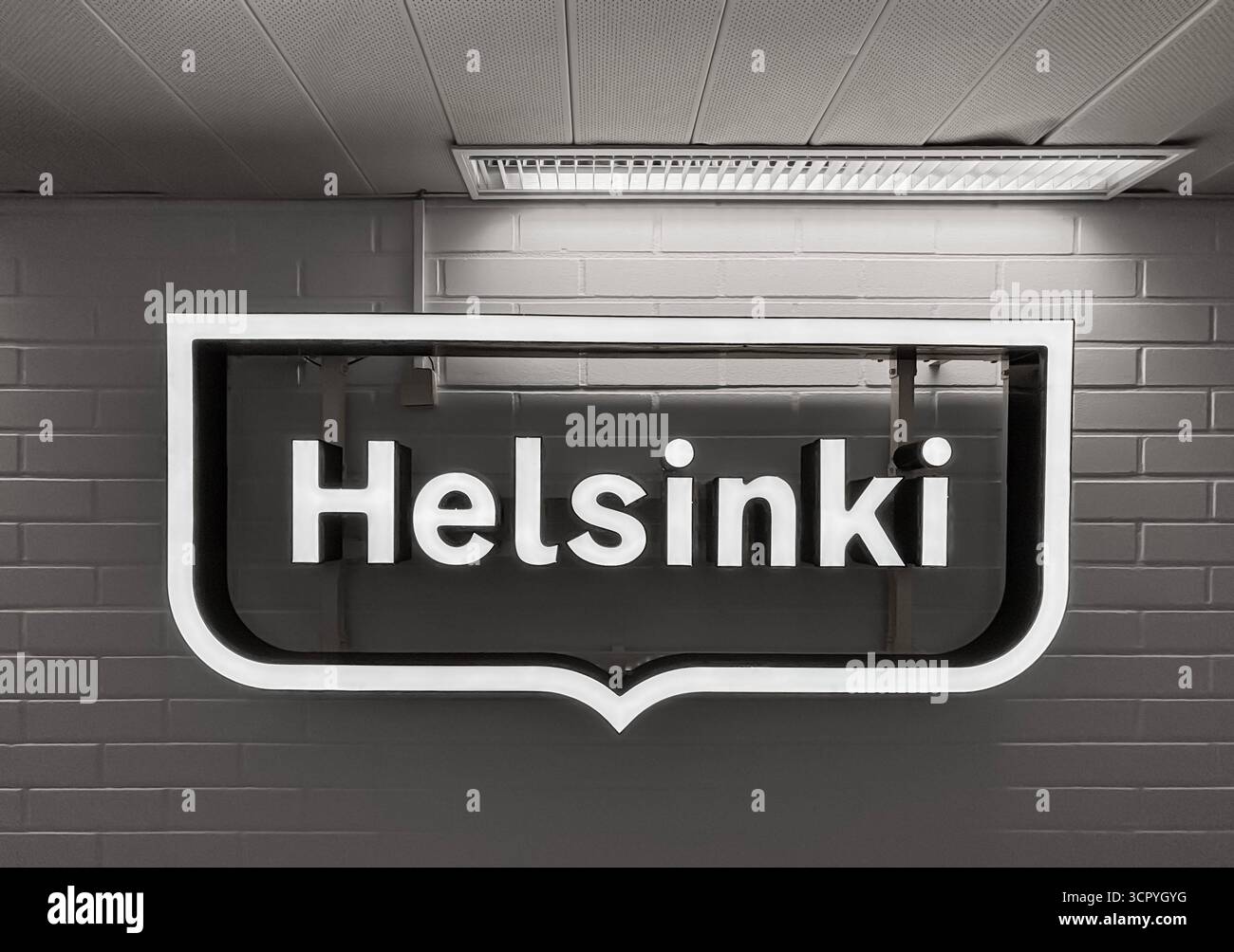 Ein beleuchtetes „City of Helsinki“-Logo an einer Wand des Bürokorridors. Graustufen. - Smartphone-aufgenommenes Stockfoto