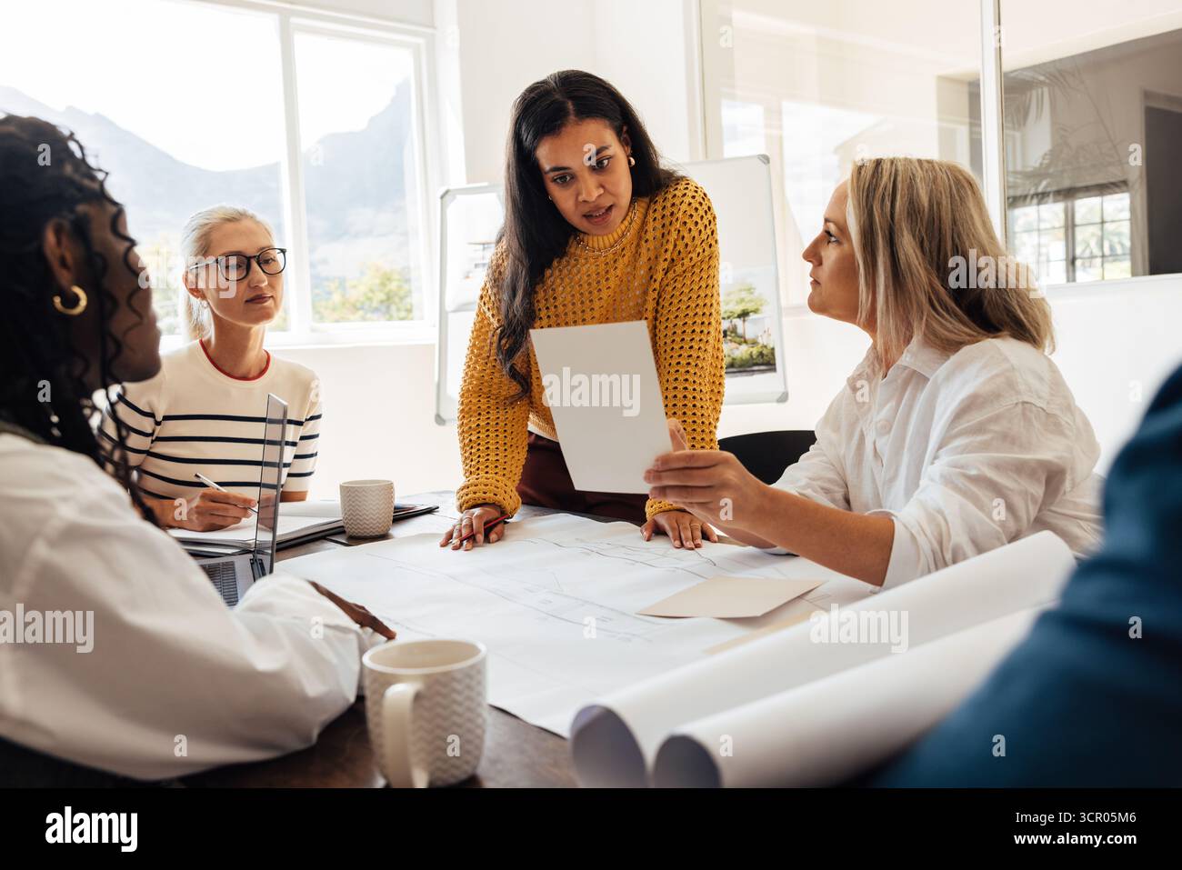 Verschiedene Gruppen von professionellen Architektinnen unterschiedlichen Alters arbeiten gemeinsam an einem Designprojekt in einem hellen Büroumfeld und demonstrieren Kollabor Stockfoto