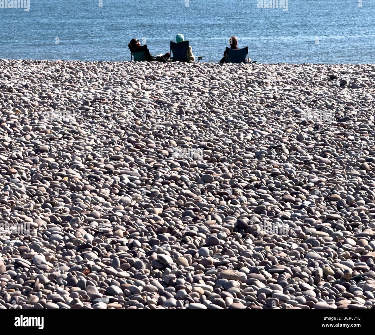 Freunde, die sich am Kiesstrand von Budleigh Salterton, Devon an der Südküste Englands entspannen. Stockfoto