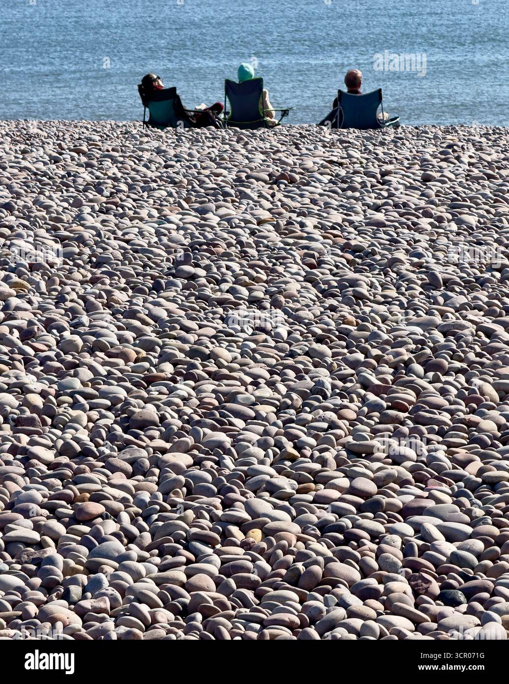 Freunde, die sich am Kiesstrand von Budleigh Salterton, Devon an der Südküste Englands entspannen. Stockfoto