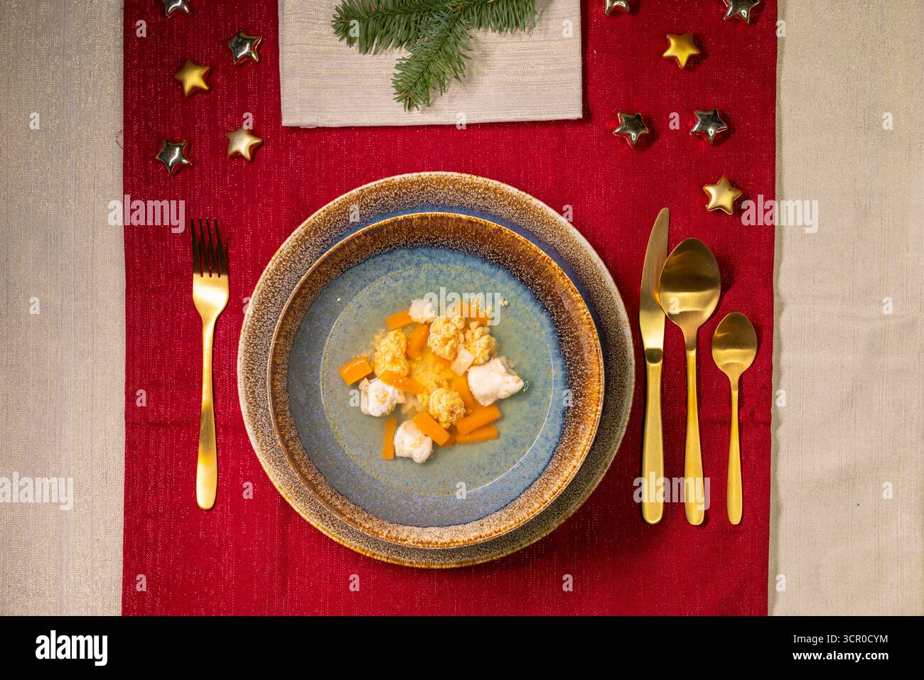 Festlicher Tisch für ein Weihnachtsessen mit Suppenschüssel und goldenem Besteck Stockfoto