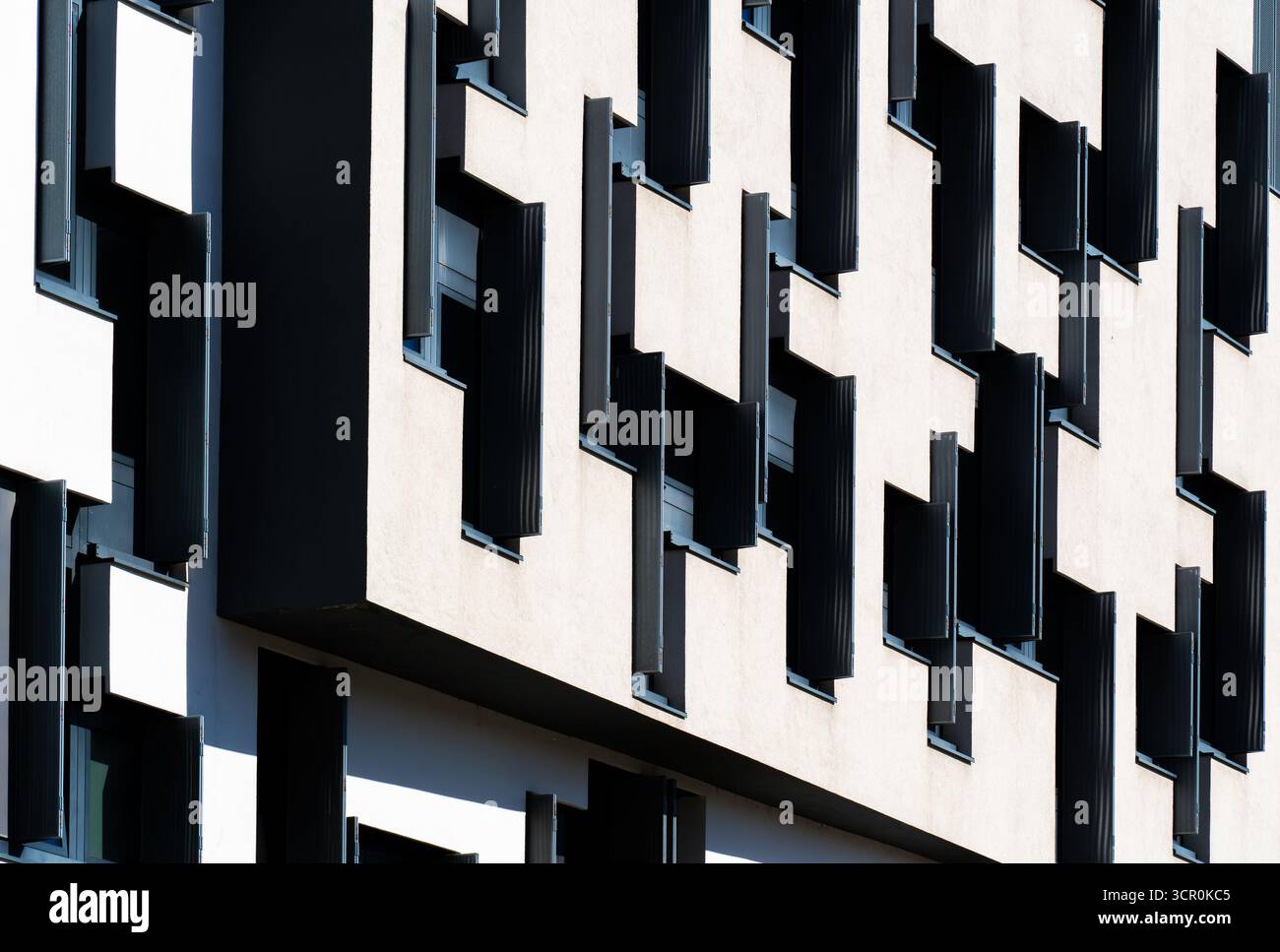 Modernes Bürogebäude mit geometrischer schwarz-weißer Fassade mit unregelmäßigem Fenstermuster und starkem Kontrast Stockfoto
