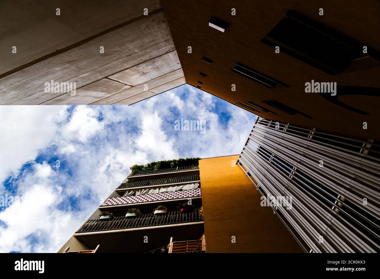 Moderner Wohnkomplex mit Holzfassadenelementen und offenen Balkonen, die eine warme, zeitgenössische Atmosphäre im Innenhof schaffen Stockfoto