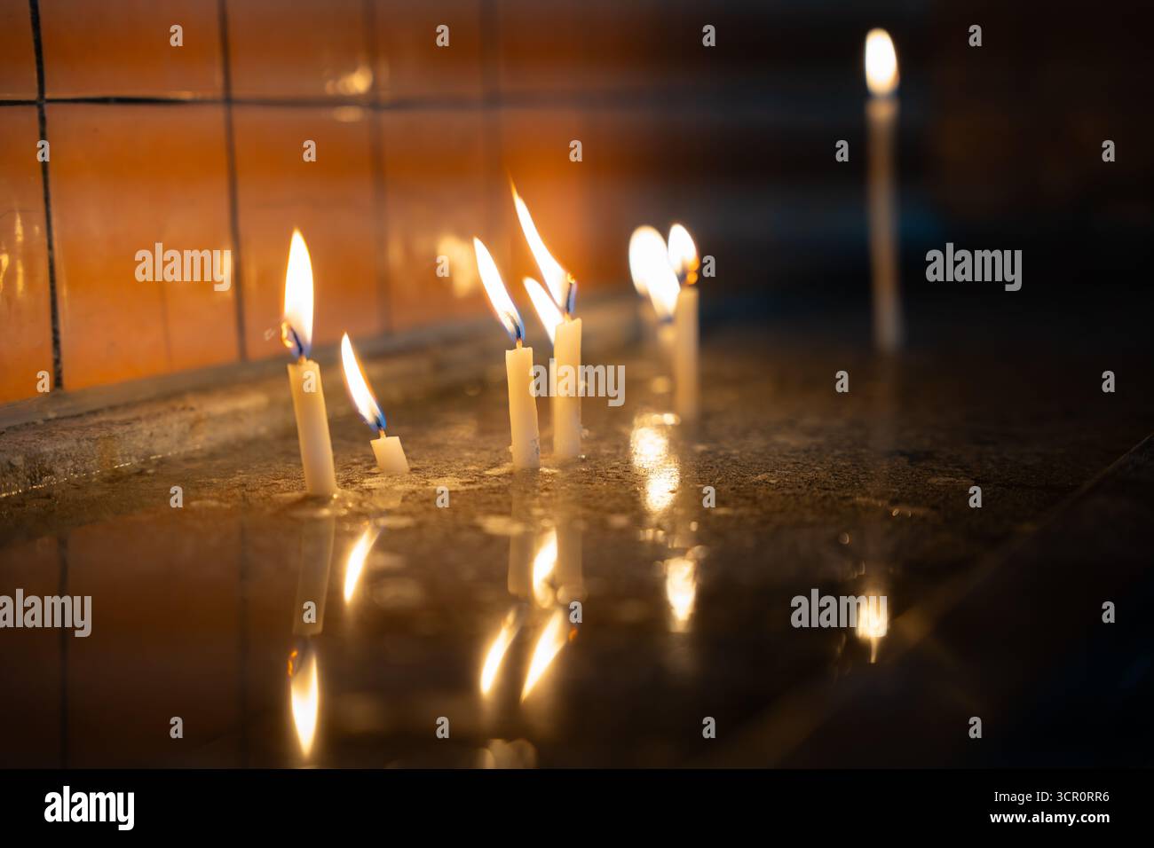 Kerzen brennen in der Kirche, reflektieren auf nasser Oberfläche. Flimmernde Hoffnung im Dunkeln. Leises Licht in stilem Wasser. Gebet und Anbetung Stockfoto