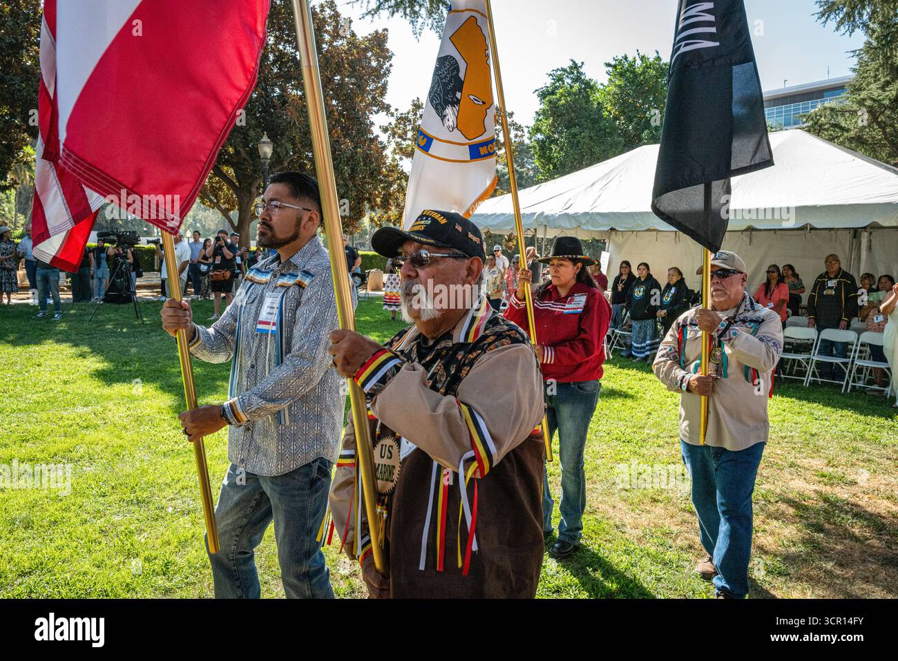 Teilnehmer, darunter ein US-Marine-Veteran, tragen Stammesflaggen, die während der Eröffnungsprozession am California Native American Day marschieren. Stockfoto