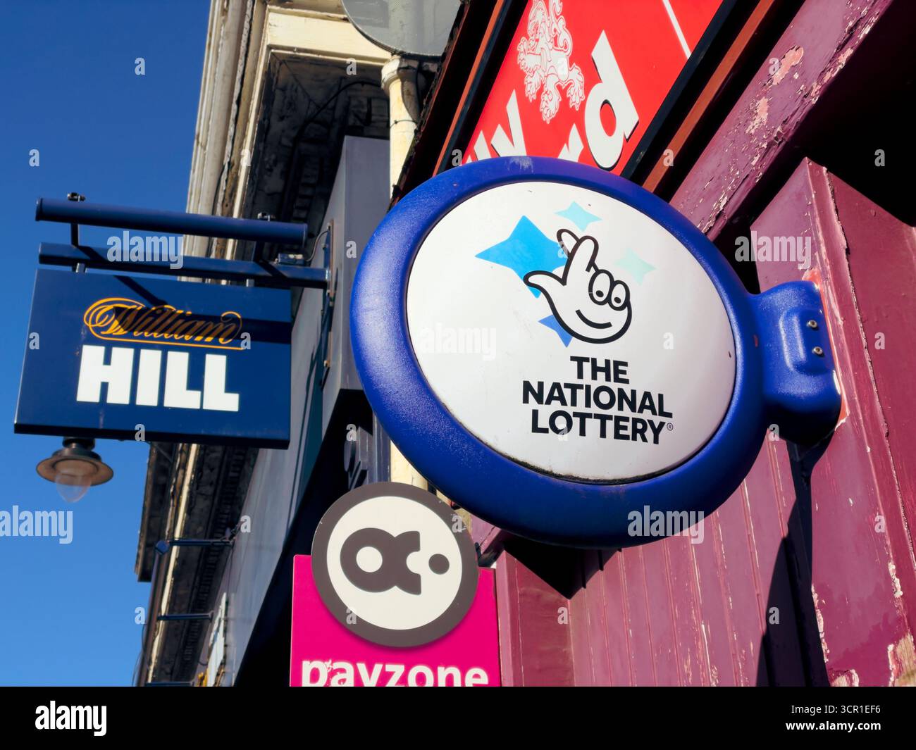 Das National Lottery-Schild vor einem 24-Stunden-Geschäft, das Lotteriescheine verkauft, Großbritannien - Smartphone-aufgenommenes Stockfoto