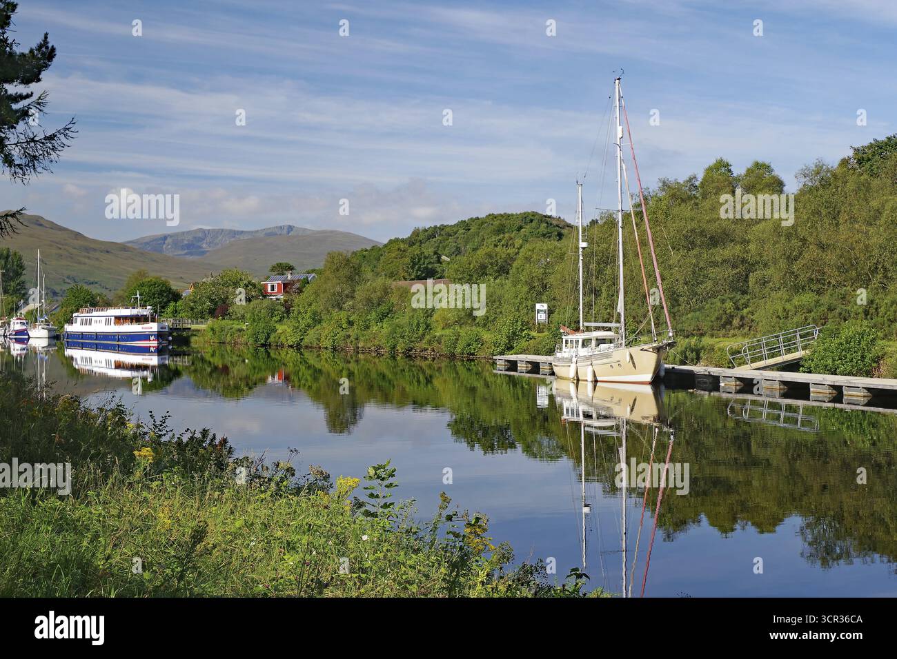 Flusslandschaft mit Booten und bewaldeten Hügeln im Hintergrund, Caledonian Canal, Fort William, Schottland, Großbritannien Stockfoto