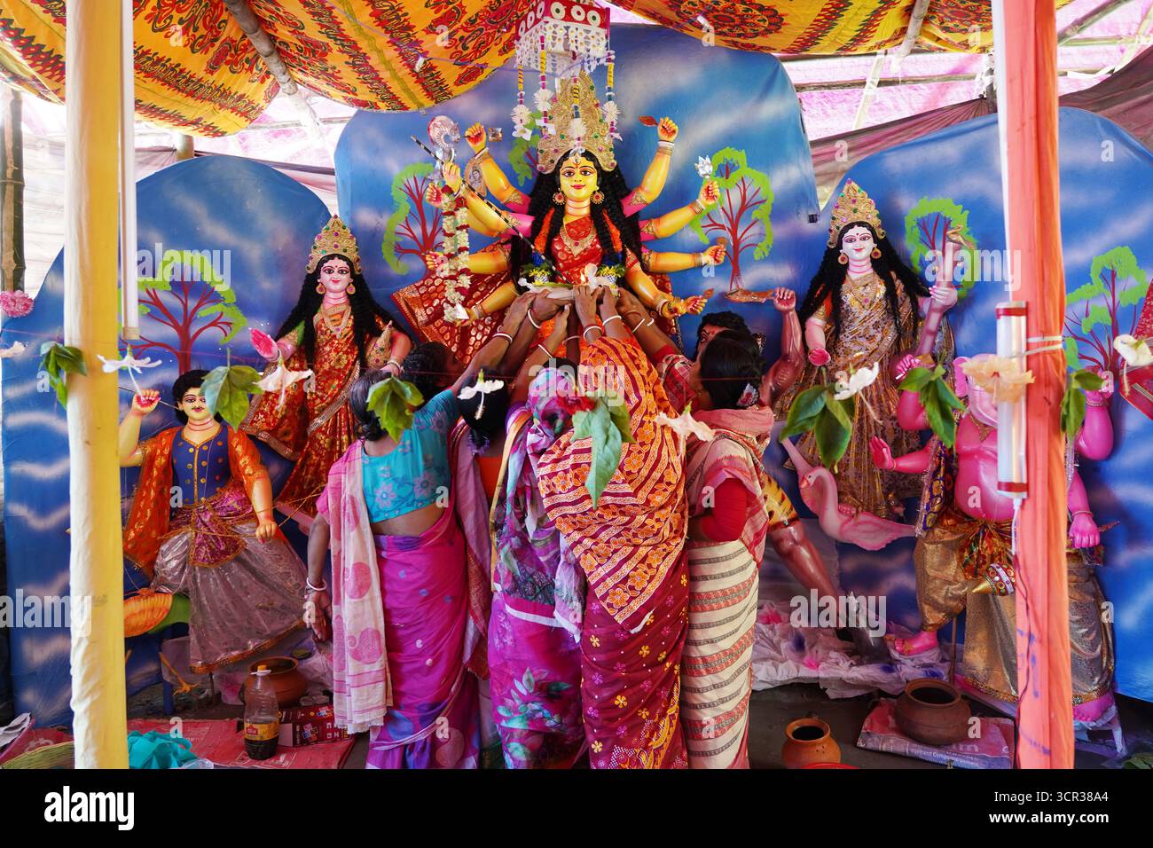 Dhaka, Dhaka, Bangladesch. September 2025. Mit der Ankunft des Herbstes in Bengalen läutet der Duft der Sheuli-Blüten das Aufkommen von Durga Puja ein. Der Rhythmus des Dhak, der Klang der Muschel und die frische Verzierung der Natur schaffen zusammen eine festliche Atmosphäre. Am 29. September 2025, dem Tag von Maha Saptami, konnte man bei der Überquerung von schlammigen Straßen und einer provisorischen Brücke aus Betelnussbäumen eine einzigartige ländliche Feier von Durga Puja im Boral Bari im Dorf Swarupkathi erleben. Mit bunten Blumen, den Takten des Dhak und der anmutigen Teilnahme von Dorffrauen, der Anbetungskredit Stockfoto