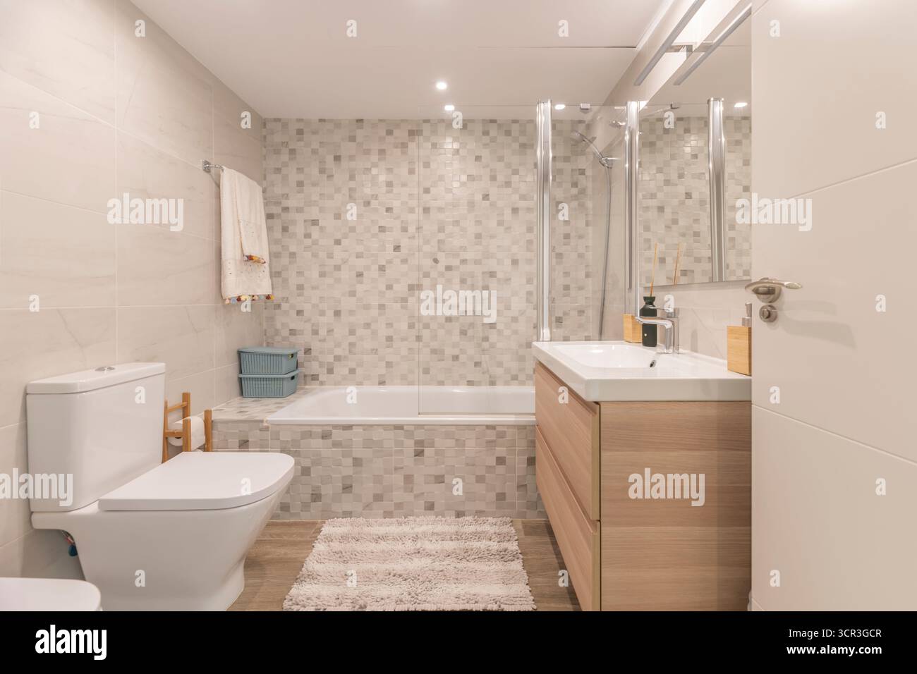 Modernes Bad mit mattschwarzem Schwebeschrank, großem runden Spiegel und indirekter Deckenbeleuchtung Stockfoto