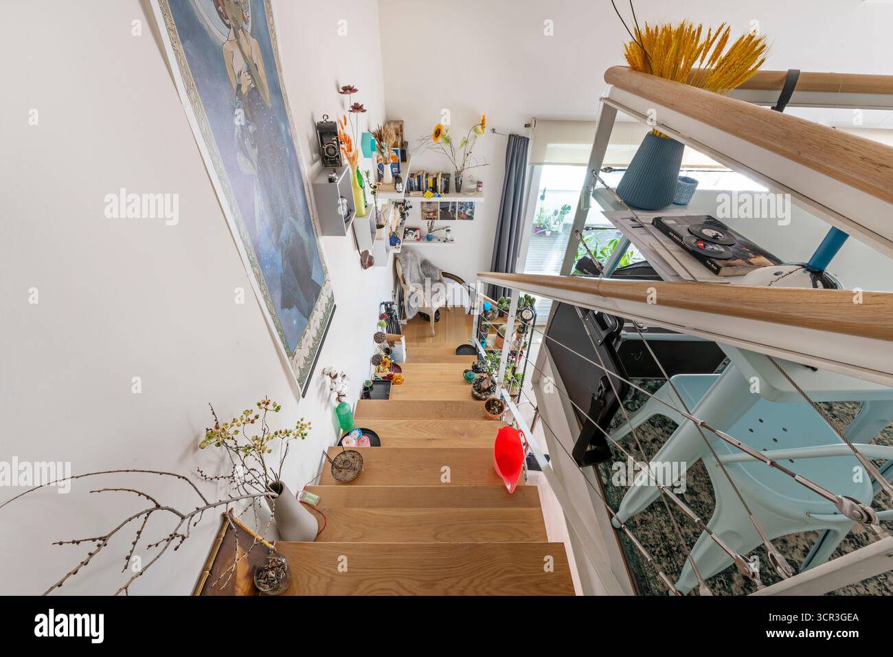 Übergangsbereich mit einer hellen Holztreppe und einem Kabelgeländer mit indirekter, gedimmter Umgebungsbeleuchtung Stockfoto