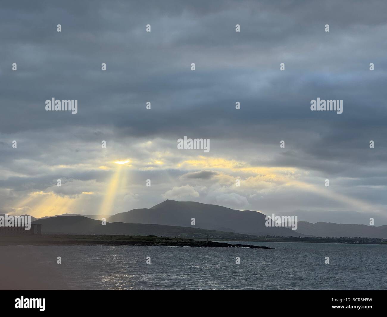 Wellen des Sonnenlichts fallen an der Küste der Ballinskelligs Bay im County Kerry, Irland. Stockfoto