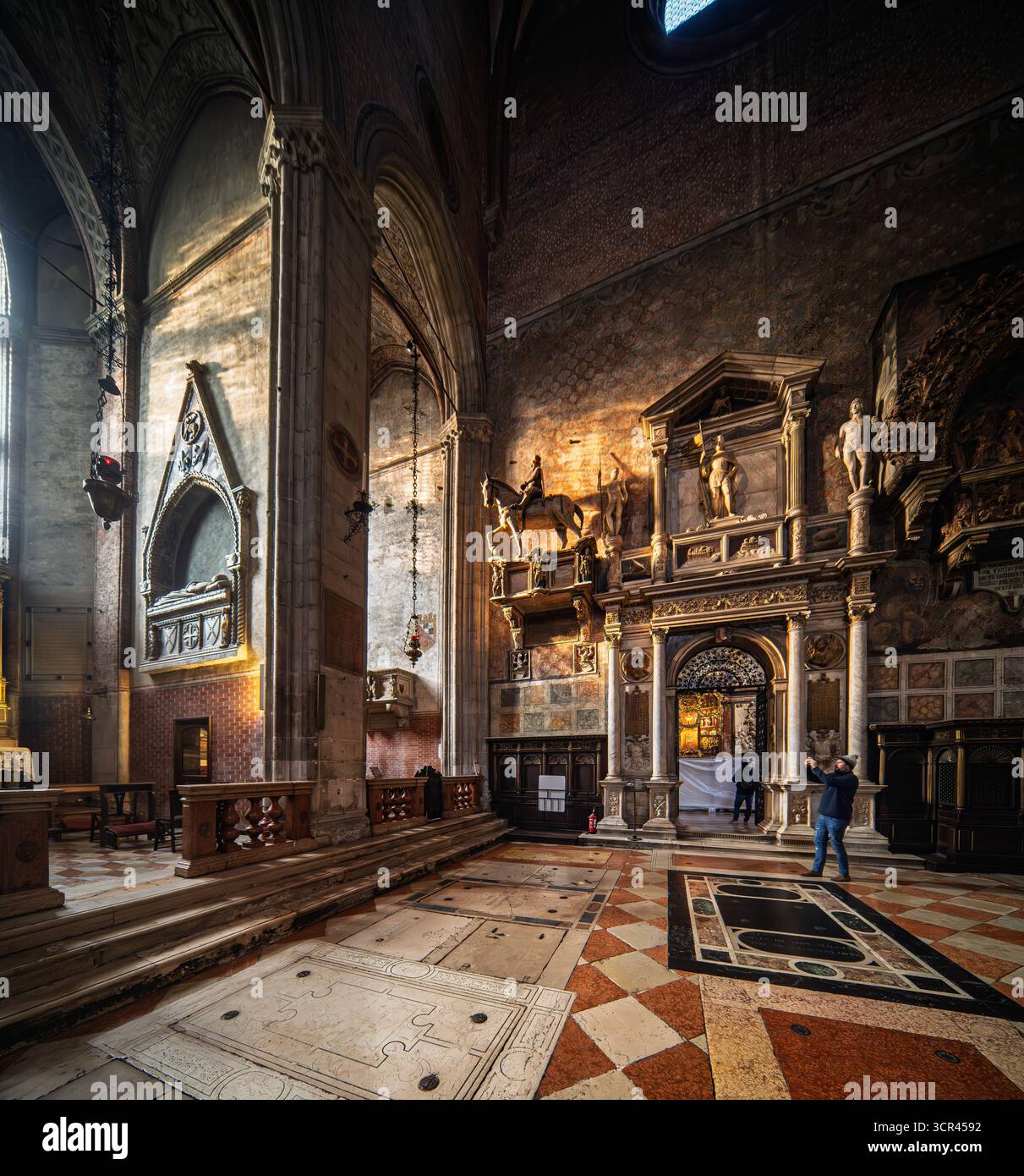 Sakristentor und Apsiskapellen in Santa Maria dei Frari, Venedig. Geschnitzter Stein und vergoldete Altäre leuchten unter geriffelten Gewölben und gefiltertem Licht. Stockfoto