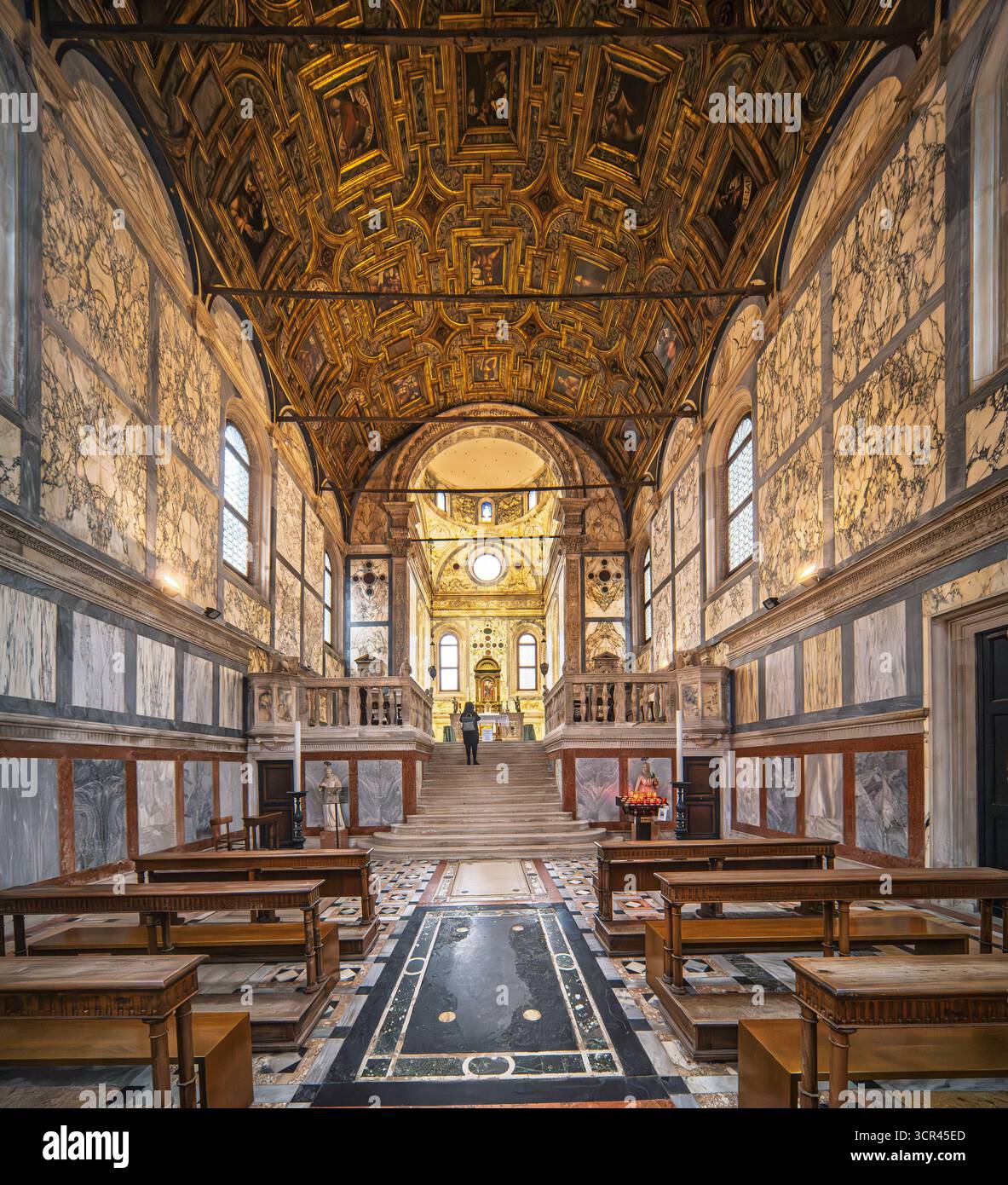 Sanftes Licht strömt durch Bogenfenster auf das marmorverkleidete Kirchenschiff von Santa Maria dei Miracoli. Der Hochaltar ist von einem strahlenden kassettenbalken eingerahmt Stockfoto