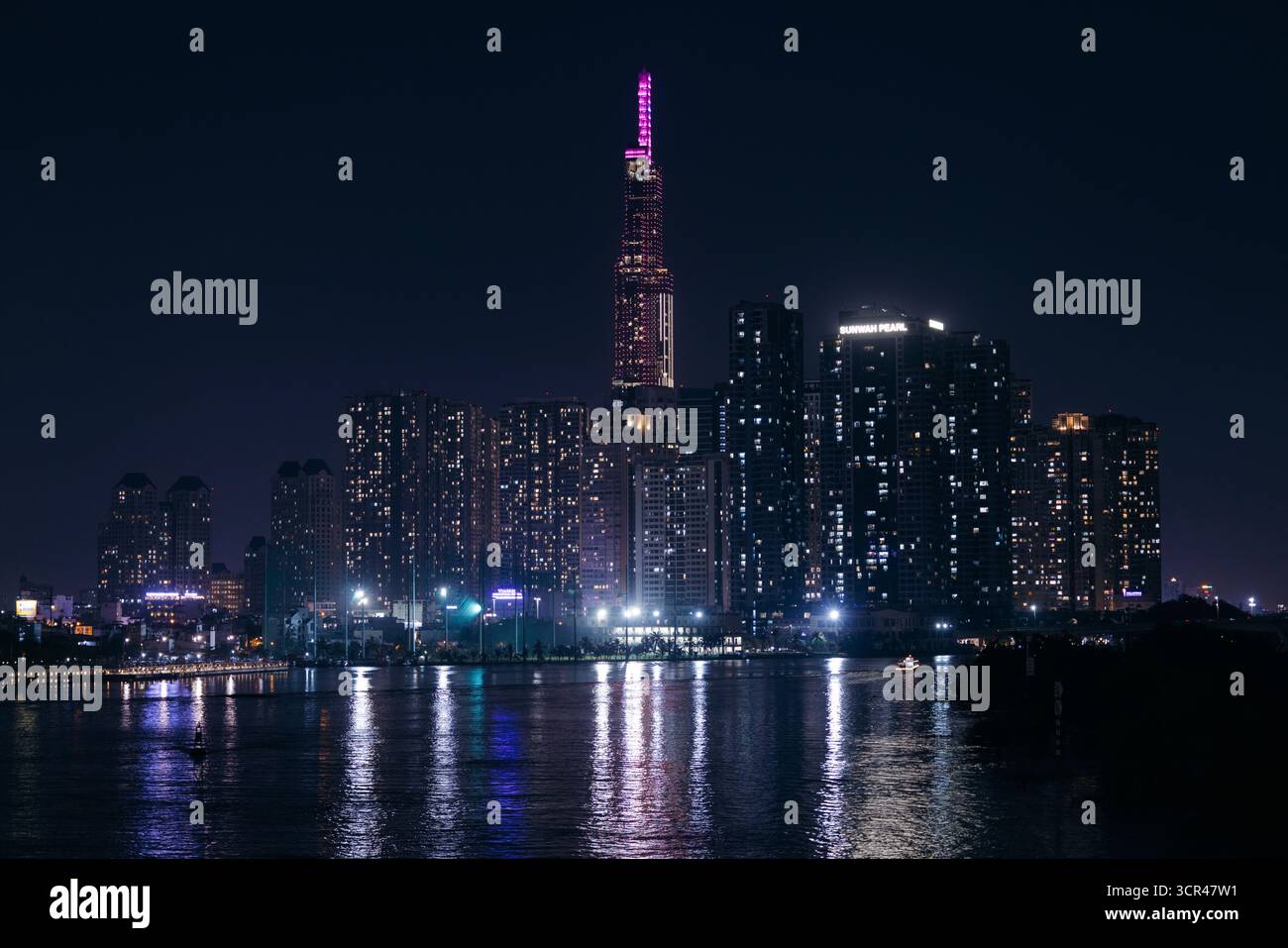 Beleuchtete Wolkenkratzer spiegeln sich in einem ruhigen Fluss während einer klaren Nacht in einer Stadtlandschaft. Ho-Chi-Minh-Stadt, Vietnam Stockfoto