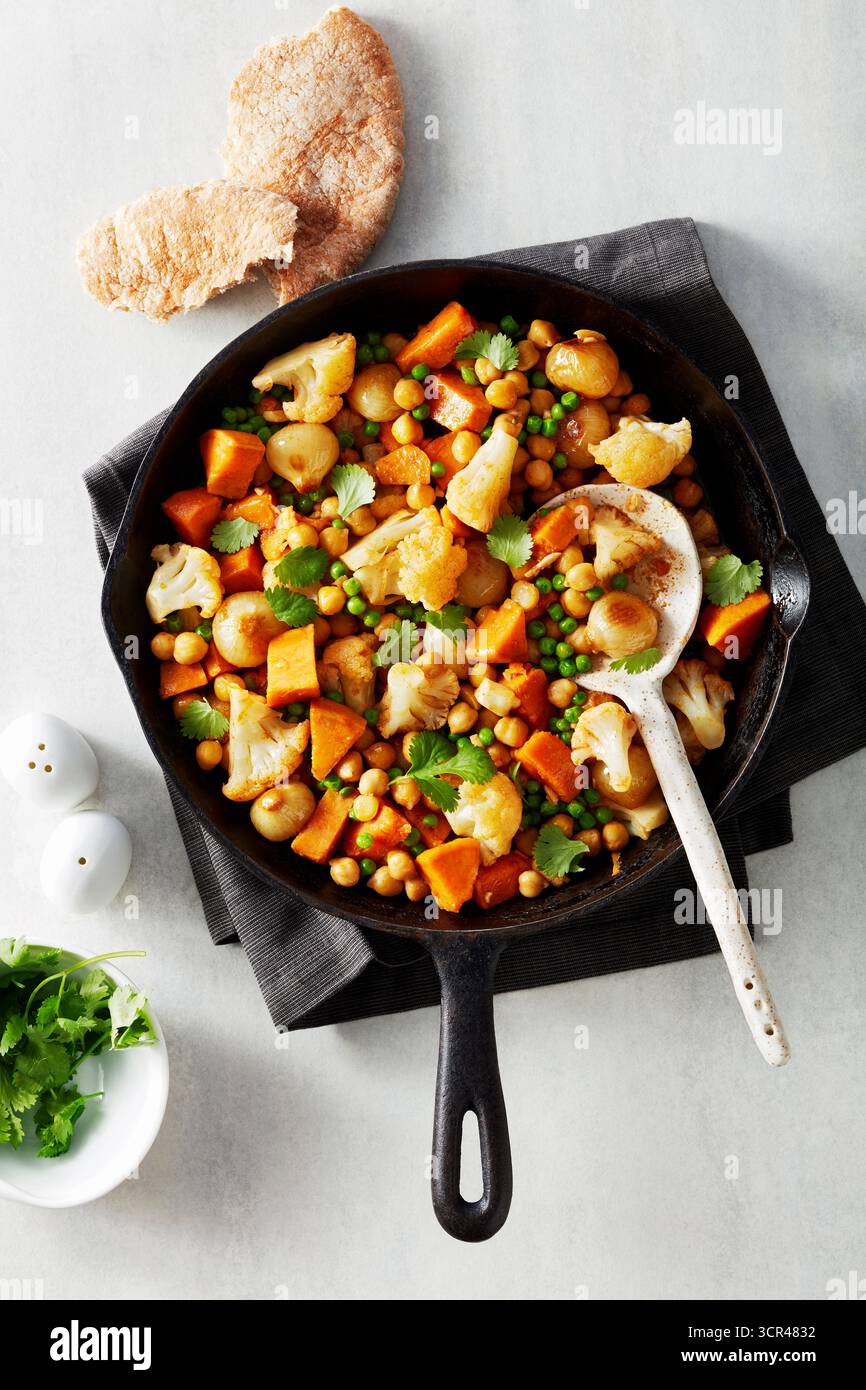 Bratpfanne mit lebendigem Gemüse-Curry einschließlich Blumenkohl, Erbsen und Süßkartoffeln. Stockfoto