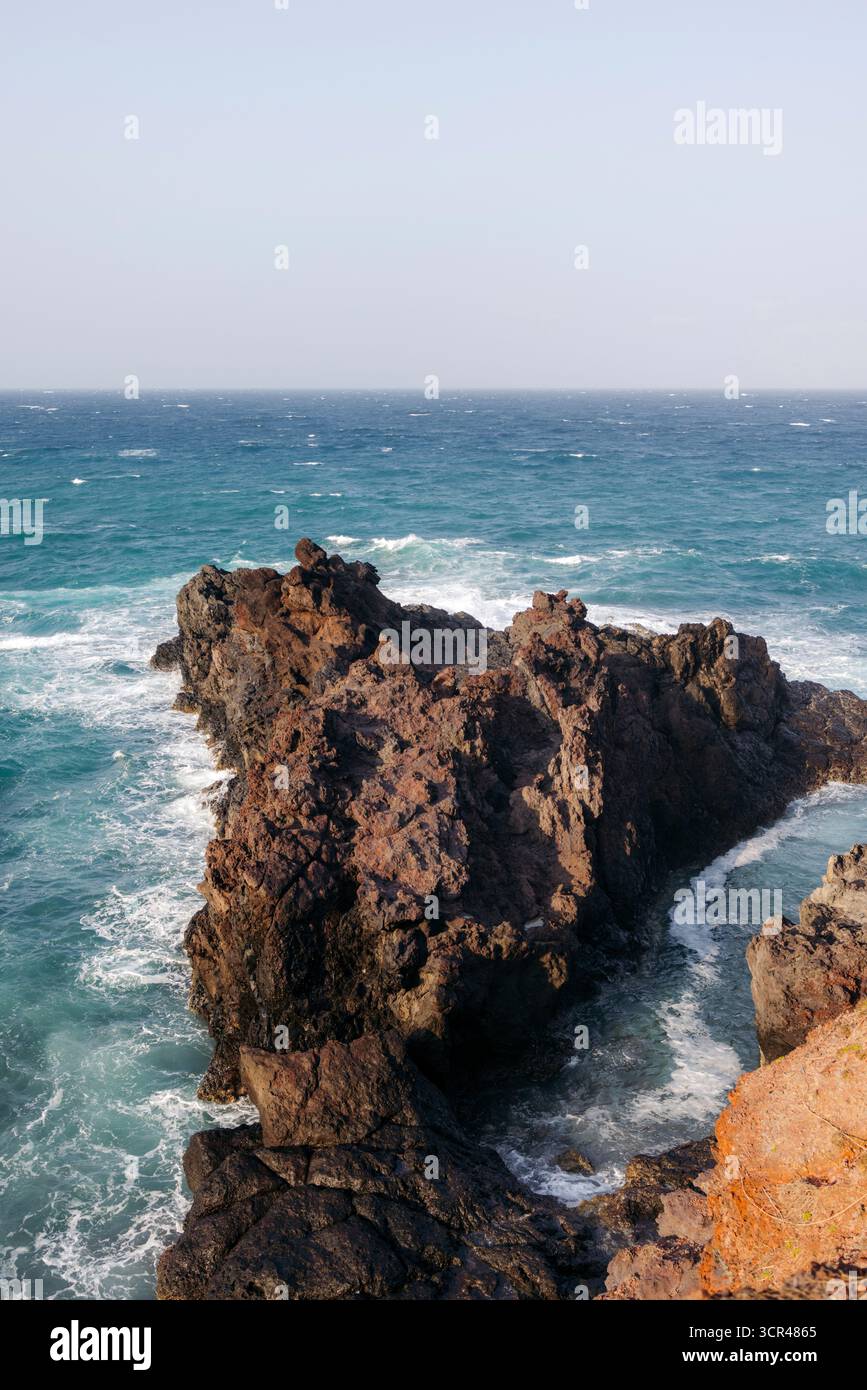 Felsige Küste mit Wellen, die gegen die zerklüfteten Klippen prallen und einer klaren blauen Meereskulisse. Phu Quy Island, Bnh Thuan, Vietnam Stockfoto