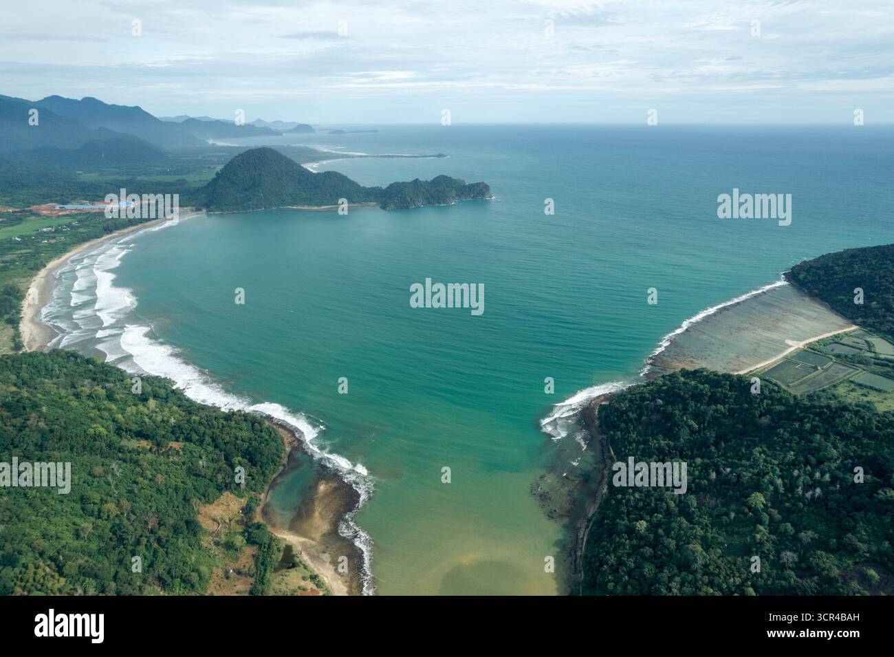 Aus der Vogelperspektive auf eine malerische Küstenbucht mit türkisfarbenem Wasser und üppig grünen bewaldeten Hügeln. Aceh Jaya Regency, Aceh, Sumatra, Indonesien Stockfoto