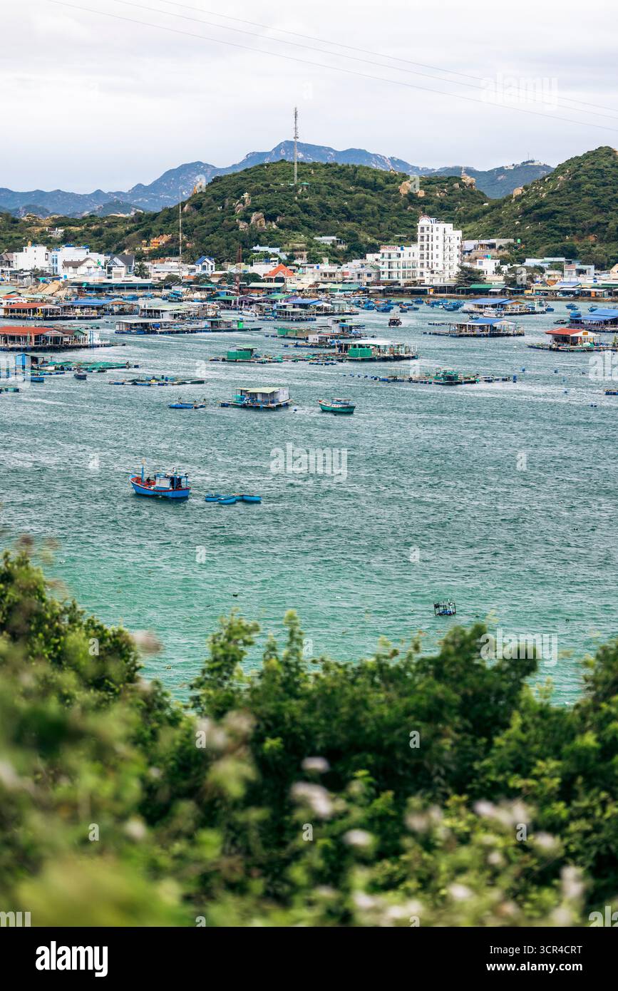 Küstenstadt mit Fischerbooten in einer türkisfarbenen Bucht und Bergen im Hintergrund. Ninh Hai District in Ninh Thuan, Vietnam Stockfoto